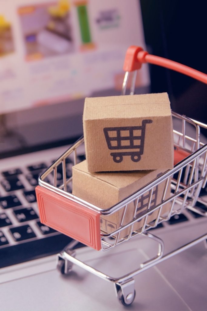 Laptop keys beneath a small wheeled cart holding packages